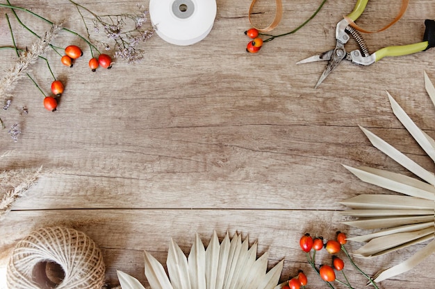 Marco hecho de accesorios de floristería y materiales naturales en una mesa de madera con espacio de texto