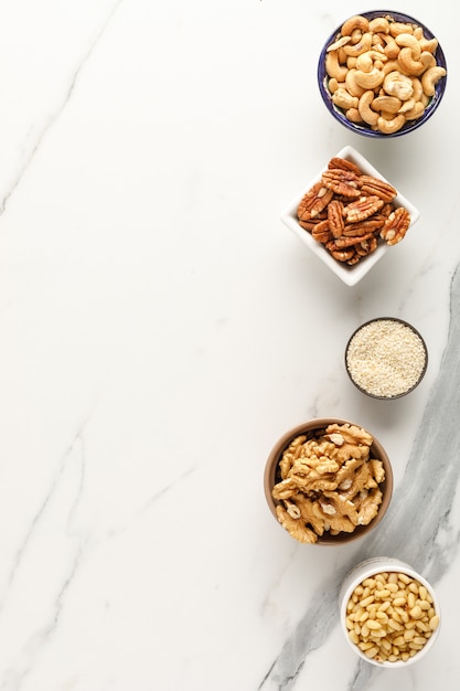 Foto marco hecho de diferentes tipos de nueces en cuencos. vista superior. copia espacio