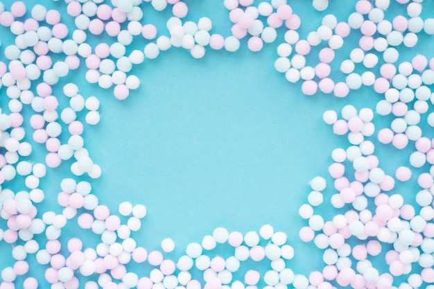 Foto marco hecho de mini pompones de bolas de colores pastel sobre un fondo azul claro con espacio de copia redonda.