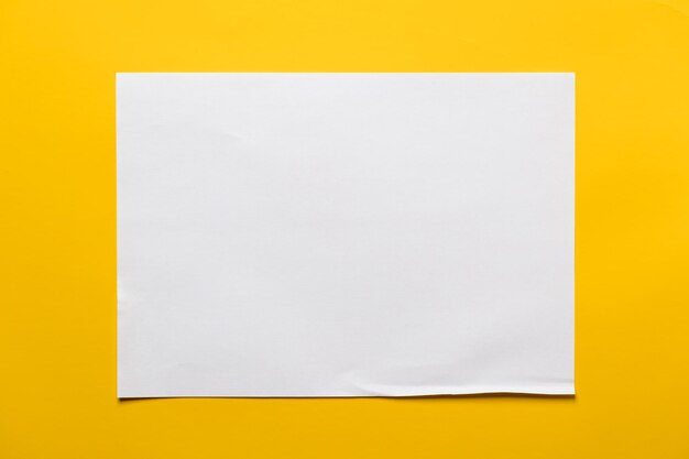 Foto marco de una hoja de papel blanco sobre un fondo amarillo espacio de copia vista superior