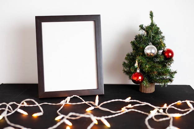 Marco de imagen y árbol de Navidad sobre una mesa con luces y decoración.