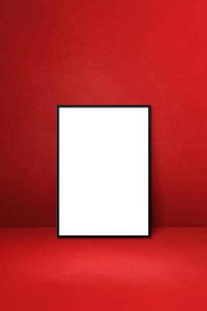 Marco de imagen negro apoyado en una pared roja. Plantilla de maqueta en blanco