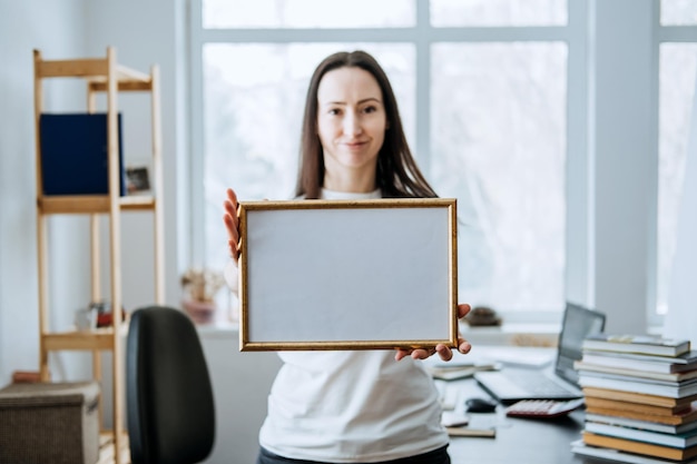 Foto marco de imagen póster modelo de certificado de diploma en manos femeninas joven mujer morena sosteniendo