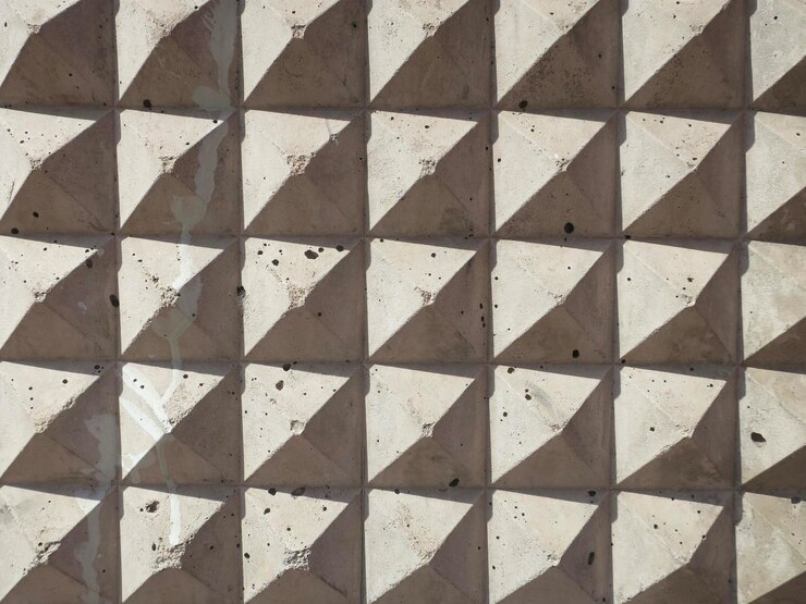 Foto un marco lleno de formas de pirámide con su sombra en una pared de piedra