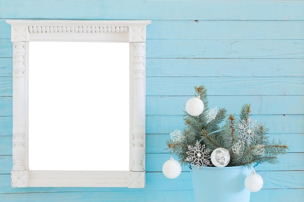 Marco de madera blanca con decoración navideña sobre fondo de madera azul