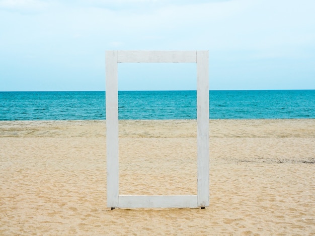 Un marco de madera en blanco blanco que puede ver a través del paisaje marino, la playa, el mar y el cielo azul