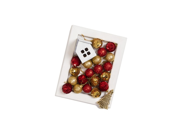 Marco de madera con decoración navideña de adornos rojos y dorados árbol dorado y casa de madera.
