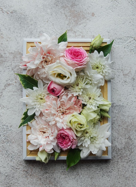 Marco de madera decorado con flores rosas y blancas.