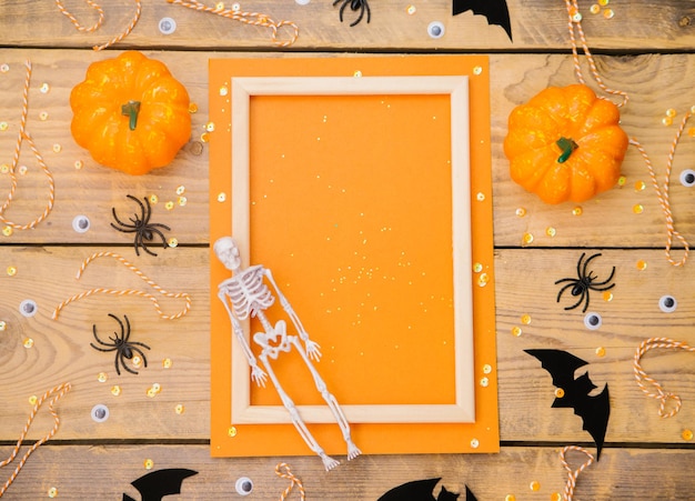 Marco de madera con esqueleto de calabaza, arañas y murciélagos sobre un fondo de madera Un tema festivo de Halloween Espacio vacío para texto