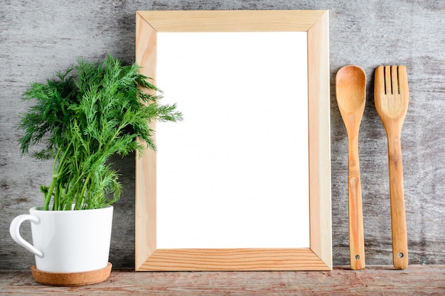 Un marco de madera vacío y accesorios de cocina en una pared gris.