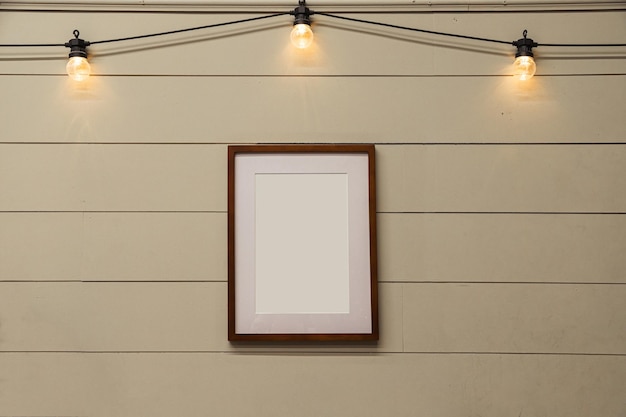 Marco de madera vacío en la pared de madera con guirnaldas y bombillas en la maqueta superior