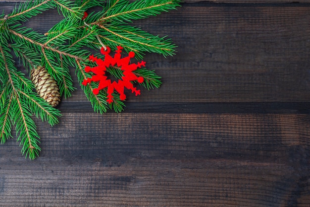 Marco de Navidad de las ramas de abeto y colgar adornos rojos sobre fondo de madera rústica