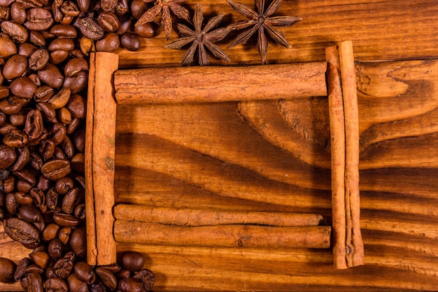 Marco de palitos de canela, granos de café y anís estrellado en una mesa de madera rústica