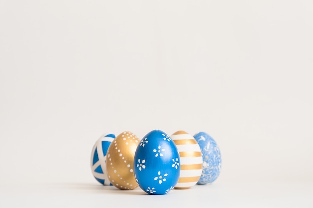 Marco de Pascua oro decorado huevos en nido aislado en superficie blanca. Concepto mínimo de pascua.