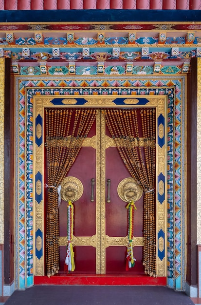 Marco de la puerta roja decorado con vino alrededor de la puerta de entrada dentro del Padmasambhava Vihara del Monasterio de Namdroling