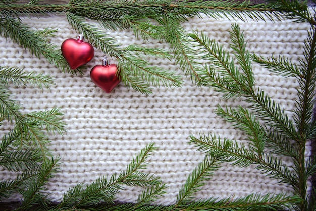 Marco de ramas y corazones de árbol de Navidad sobre fondo de punto