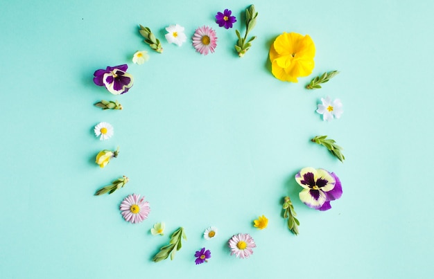 Marco redondo de círculo de flores de primavera, detalles planos laicos sobre fondo verde. Concepto de naturaleza de diseño minimalista