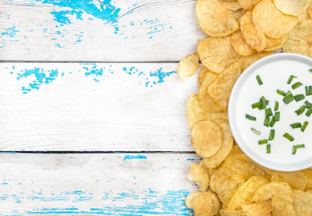 Marco de tazón con crema agria y papas fritas en la vieja mesa de madera Vista superior