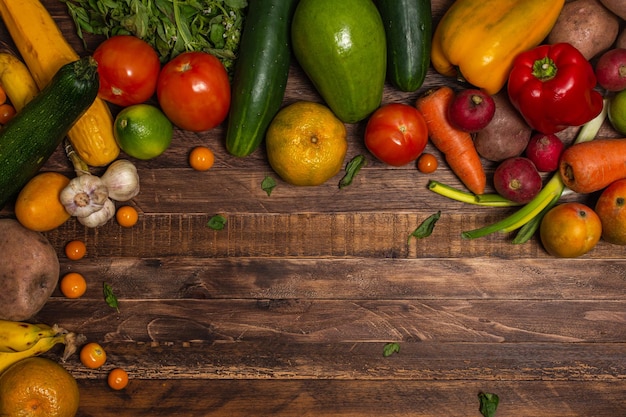 Marco de una variedad de frutas y verduras frescas sobre fondo de madera Concepto vegano