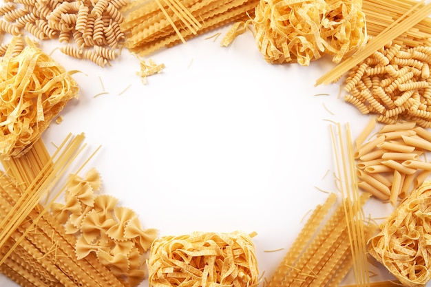 Marco de una variedad de variedades de papel tapiz de pasta. Mezclar macarrones, espaguetis sobre fondo blanco con espacio de copia