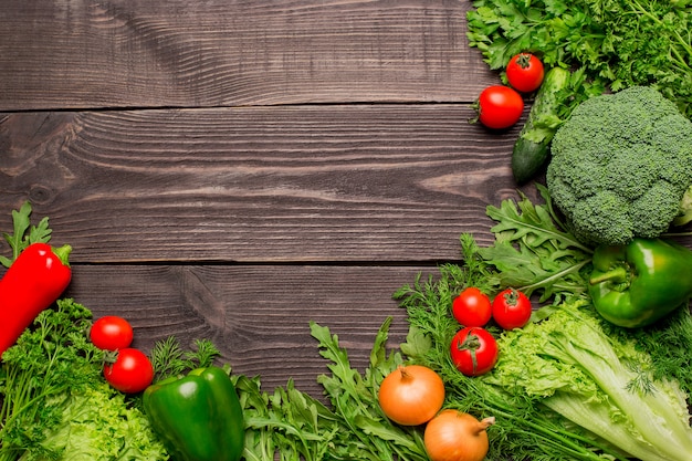 Marco de verduras frescas verdes y rojas en la mesa de madera, vista superior, espacio de copia