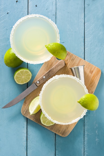 Margarita-Cocktails mit Limette im Glas auf blauem Holztisch, Draufsicht