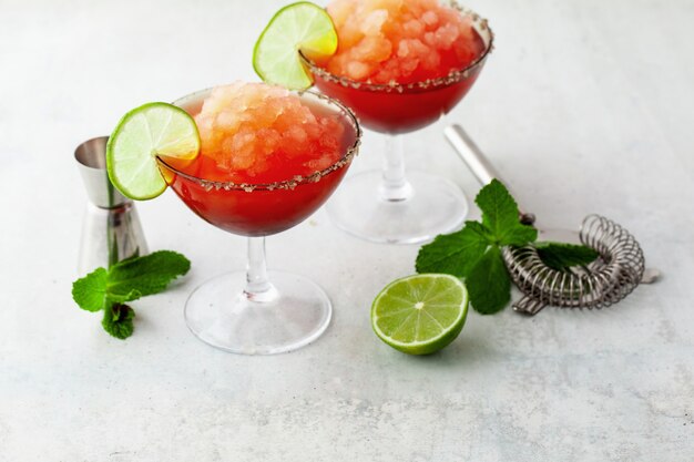 Margarita congelada vermelha, coquetel refrescante na mesa e limão com hortelã