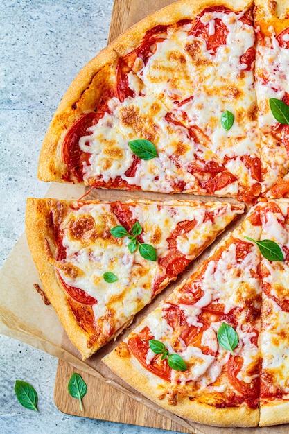 Margarita de pizza clásica con mozzarella, tomate y albahaca sobre tabla de madera