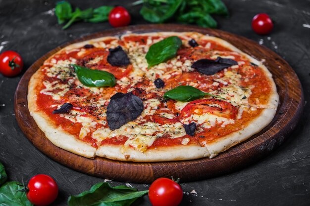 Margarita de pizza perfecta con rodajas de tomate albahaca y tomates cherry sobre una superficie oscura