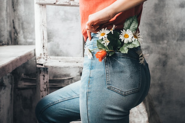 Margaritas florecientes en el bolsillo trasero Mujer posando con flores de margarita en el fondo de los pantalones vaqueros El concepto de ternura