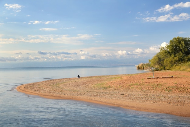 Foto margem do lago arenoso pitoresco com céu azul e nuvens em um dia de verão.