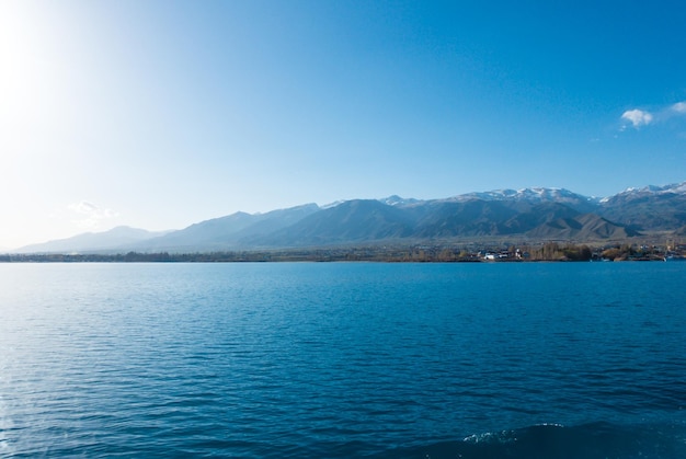 Margem sverny do lago issykkul quirguistão vista do navio para a costa água azul de um lago de montanha