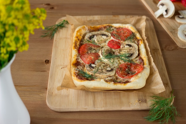 Margherita pizza casera rectangular con setas en una tabla de madera