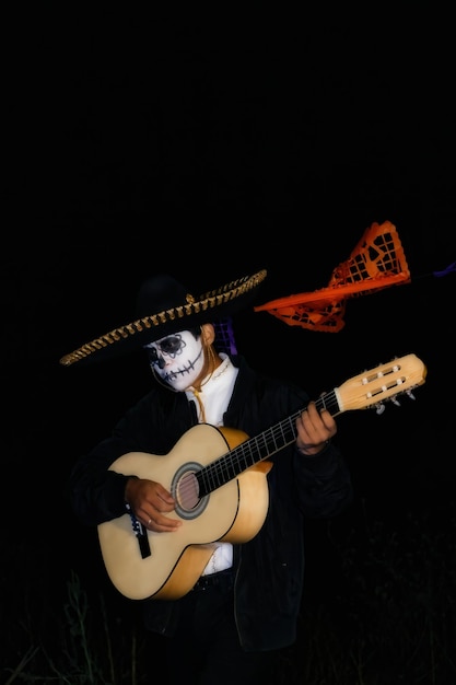 Un mariachi maquillado en el Día de los Muertos toca la guitarra bajo luces de neón
