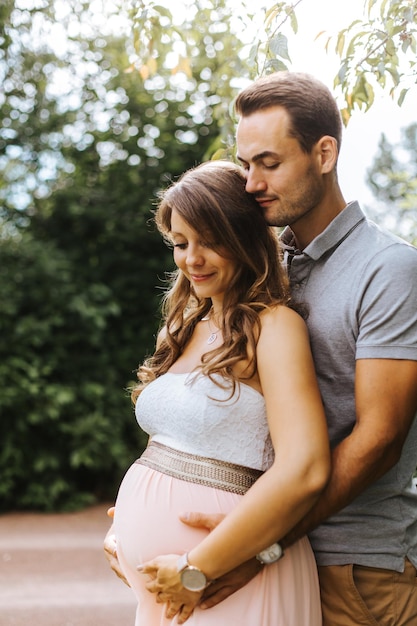 Marido abraçando esposa grávida ao ar livre