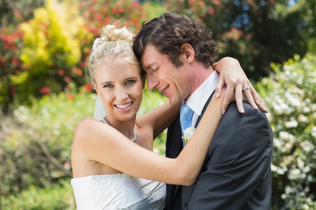 Marido abraçando sua nova esposa sorrindo para a câmera