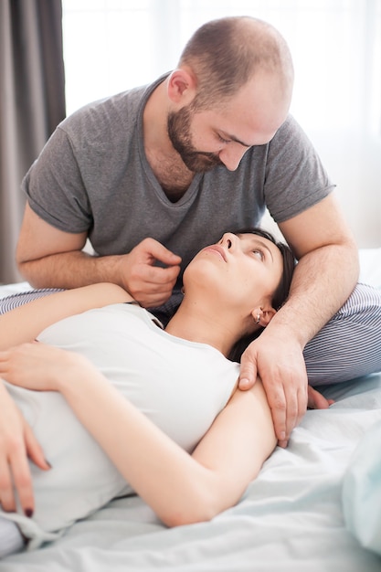 Marido barbudo en pijama mirando a su esposa después de despertarse.