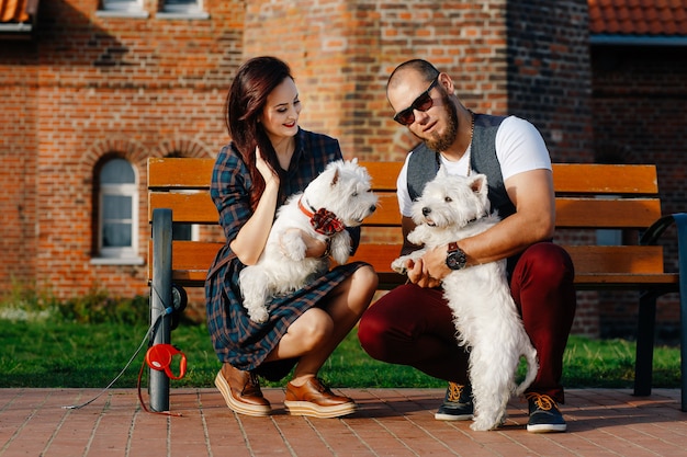 Marido con una bella esposa paseando a sus perros blancos en la calle