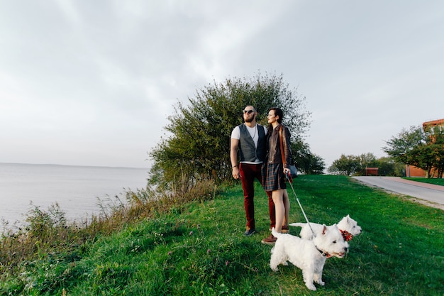 Marido con una bella esposa paseando a sus perros blancos en el parque