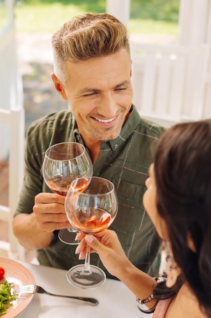 Marido bonito sorrindo enquanto bebe vinho com a esposa