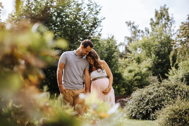 Marido com esposa grávida de mãos dadas na floresta