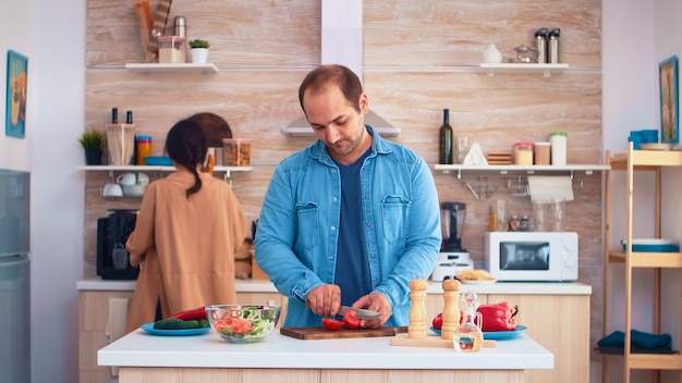 Marido cortando tomates enquanto prepara a salada com a esposa na cozinha. legumes saudáveis cozinhar preparar alimentos orgânicos saudáveis, estilo de vida feliz juntos. refeição alegre em família com legumes