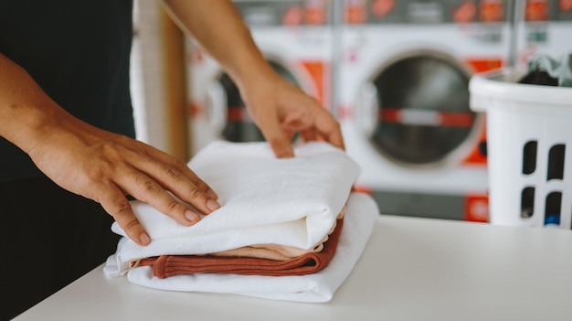 Marido da casa com cesto e roupa suja lavada roupa na lavanderia interior da máquina de lavar na loja de negócios de lavanderia