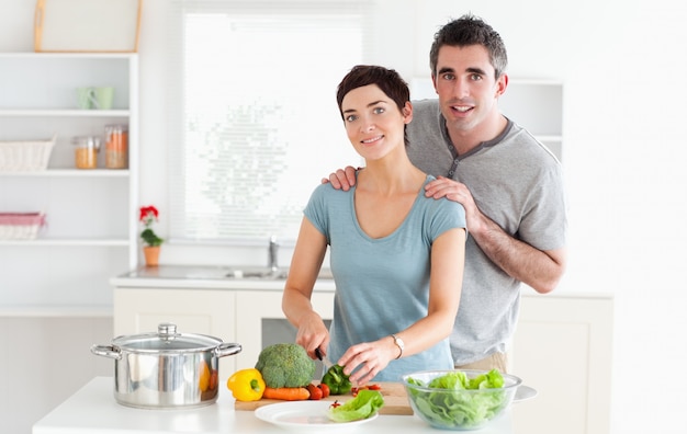 Marido dando masajes a su esposa mientras ella está cortando verduras