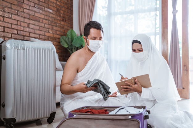 Foto marido e esposa de peregrinos muçulmanos preparam item