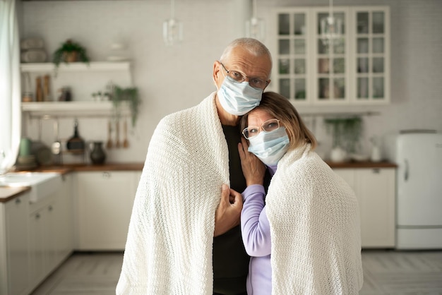 Foto marido e esposa idosos de inverno frio usando máscaras protetoras em casa