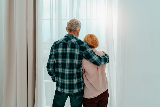 Marido e mulher aposentados se abraçam em casa