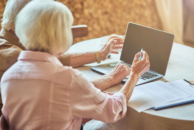 Marido e mulher idosos usando computador em casa