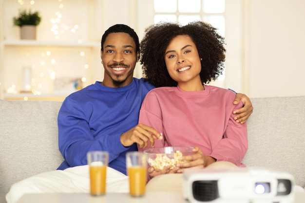 Marido e mulher negros desfrutam de um abraço na sala de estar.