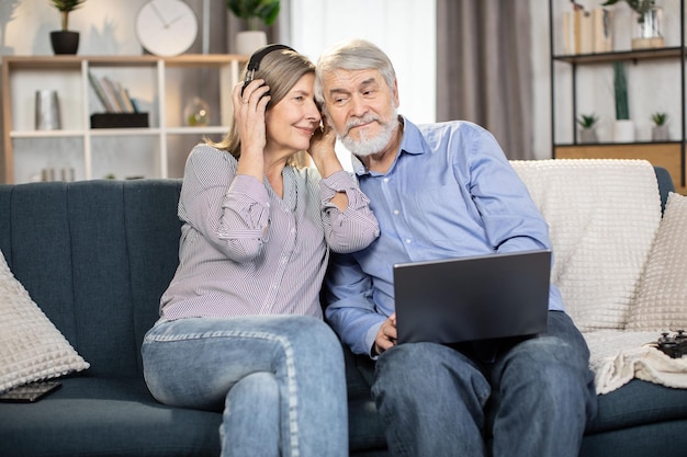 Marido e mulher ouvindo música em fones de ouvido no laptop